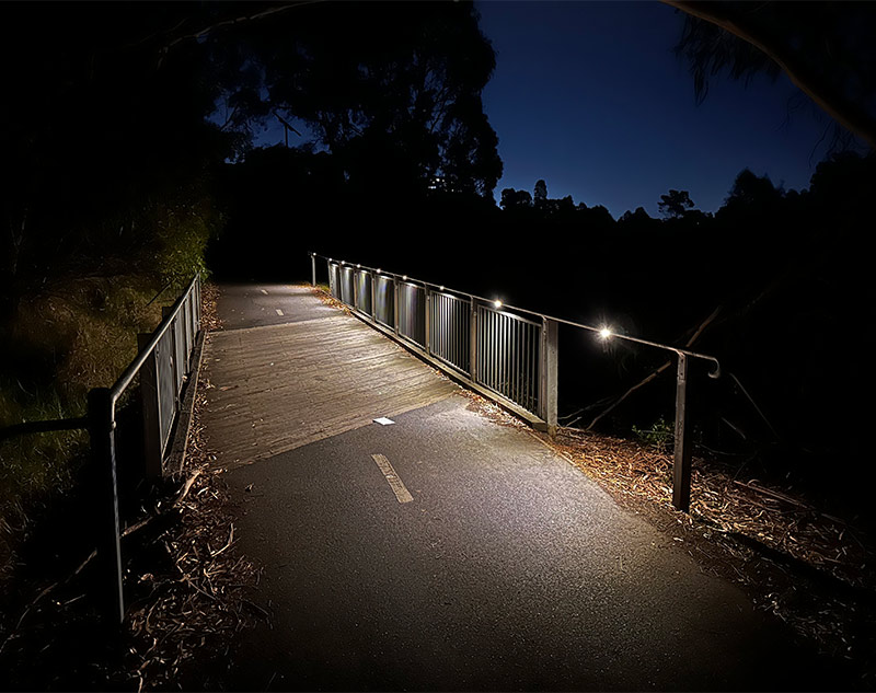 The view at night of the upgraded bridge on the Capital City Trail featuring a custom designed outdoor pathway lighting solution powered by the sun